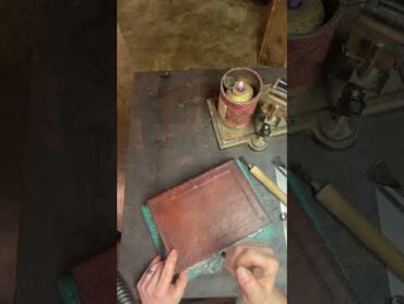 Bookbinder decorates a 500 year old book with hand tools.